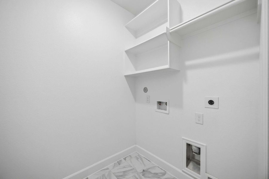 Make laundry day easier with a second-floor laundry room equipped for side-by-side washer and dryer, built-in shelving, and hanging space.