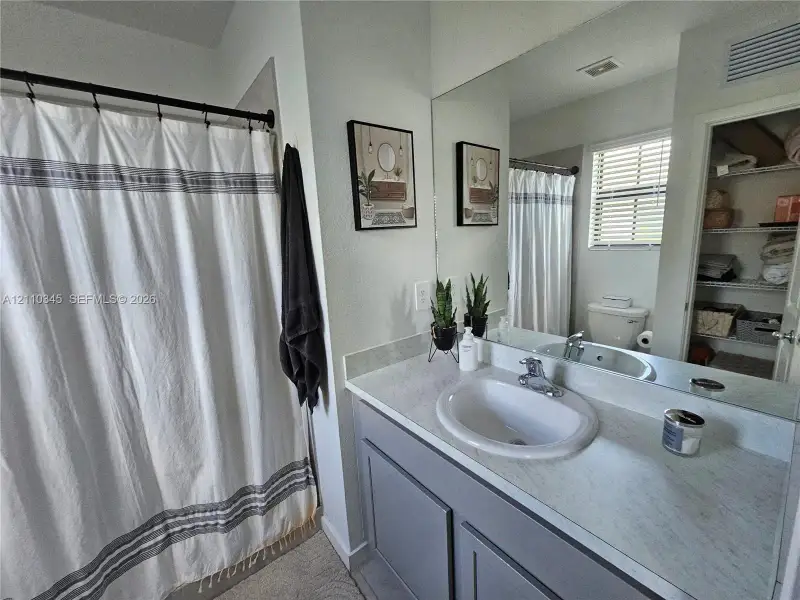 Bathroom featuring a vanity with shaker-style cabinetry, an integrated sink with a chrome faucet, a stone-finish countertop, and a full-width wall mirror