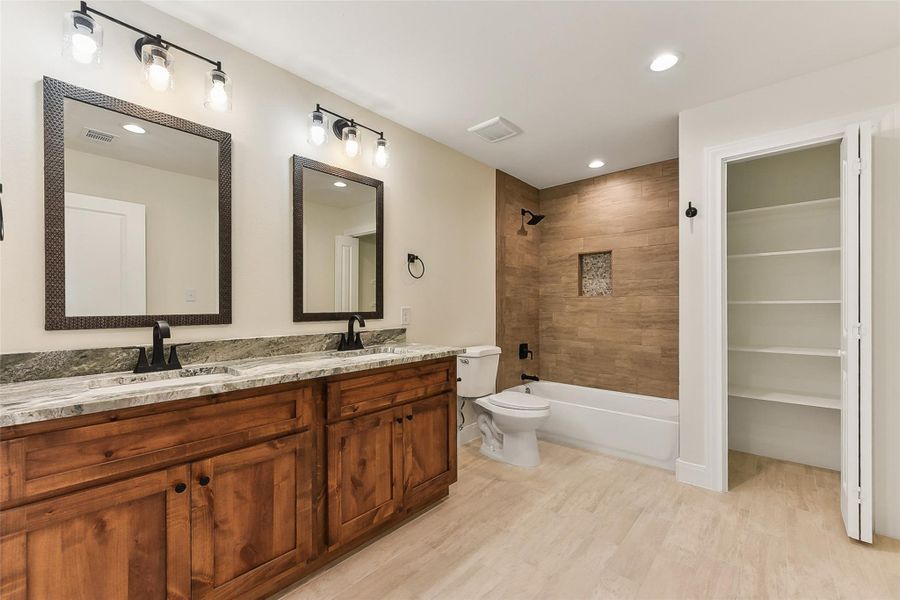Jack 'n Jill Bathroom with wood plank tile floors, visible vents, toilet, and a sink Jack 'n Jill Bathroom with wood plank tile floors, visible vents, toilet, and a sink