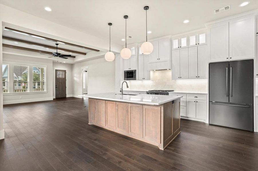 Kitchen with stainless steel appliances, beamed ceiling, ceiling fan, and white cabinetry