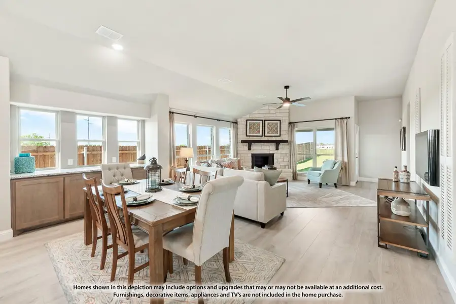 Open-plan dining and living area with stone fireplace, ceiling fan, and light wood floors Open-plan dining and living area with stone fireplace, ceiling fan, and light wood floors