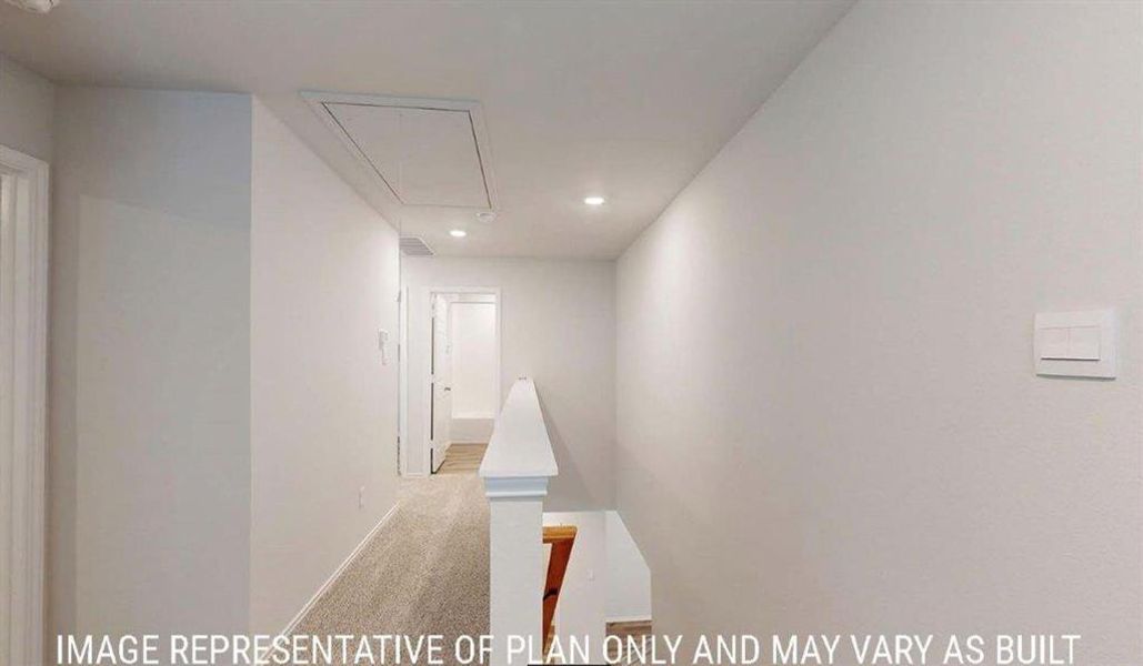 Upper-level hallway with neutral carpeting, recessed lighting, and a white balustrade