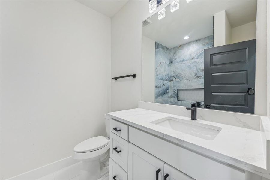 Bathroom with tile patterned floors, vanity, a tile shower, and toilet