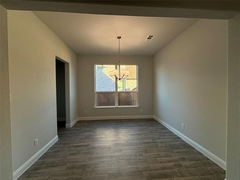 Unfurnished dining area featuring a notable chandelier and dark wood-type flooring