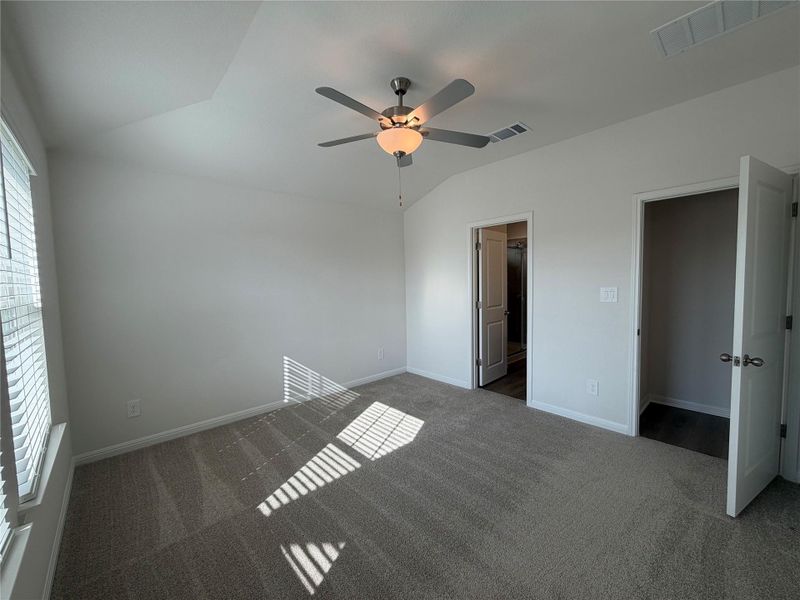 Unfurnished bedroom featuring lofted ceiling, carpet floors, ceiling fan, and a spacious closet Unfurnished bedroom featuring lofted ceiling, carpet floors, ceiling fan, and a spacious closet