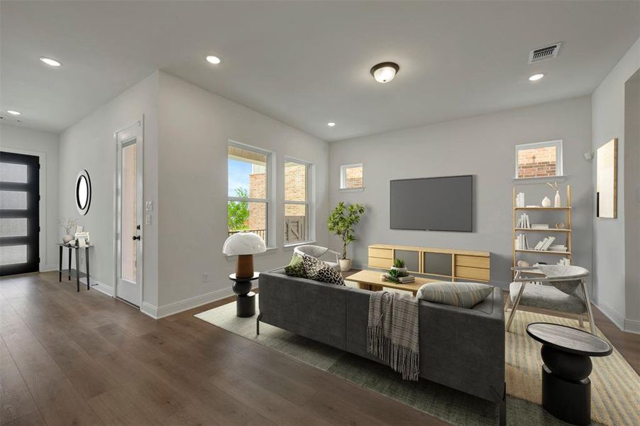Open-concept living space featuring wood-finish flooring, recessed lighting, and multiple windows