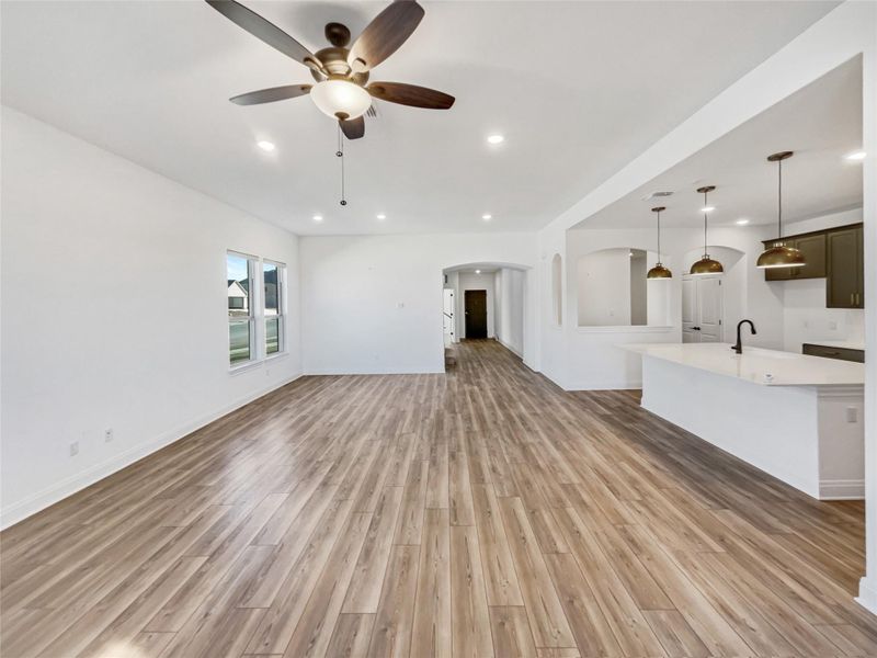 Unfurnished living room featuring arched walkways, recessed lighting, light wood-style flooring, and ceiling fan