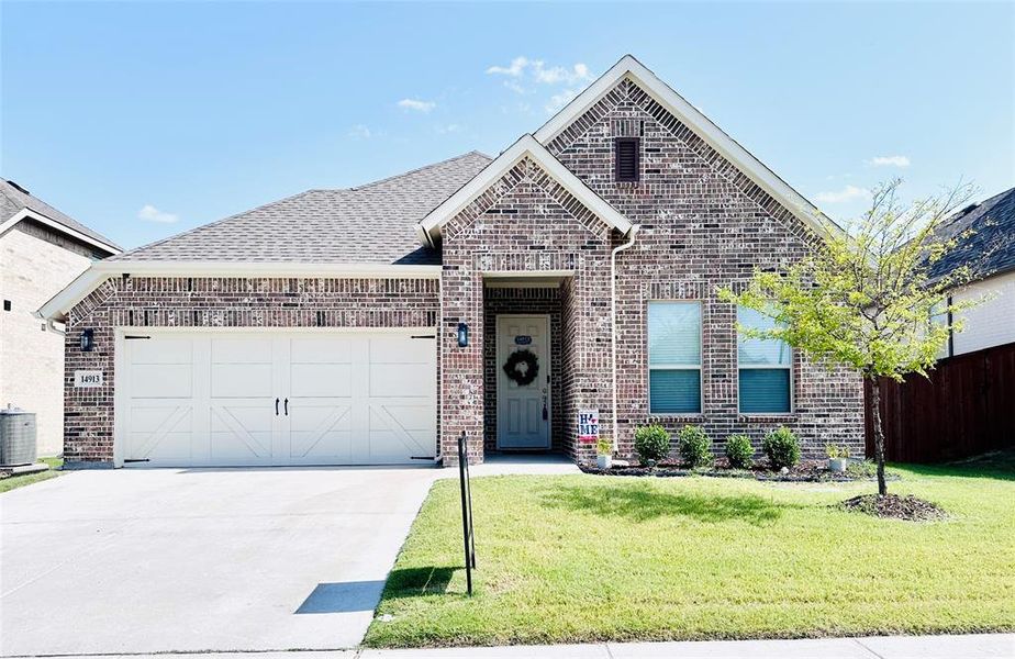 View of front of property featuring a garage, central AC unit, and a front yard