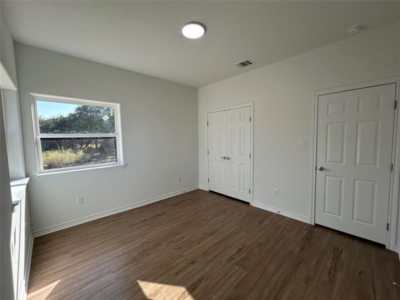 Bedroom with dark wood-type flooring and a closet