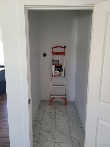 Laundry area featuring light marble finish flooring and baseboards