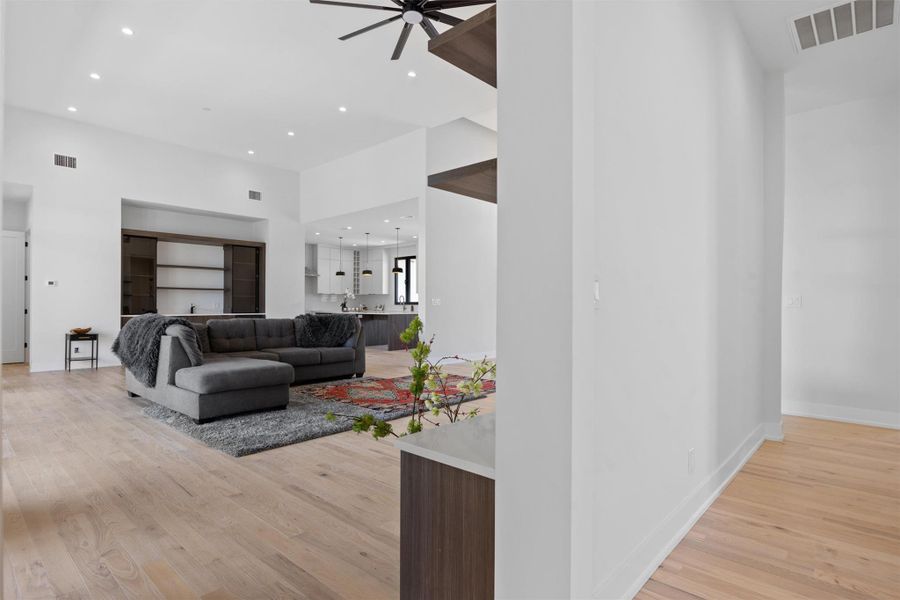 Living room featuring visible vents, light wood-style floors, and a ceiling fan