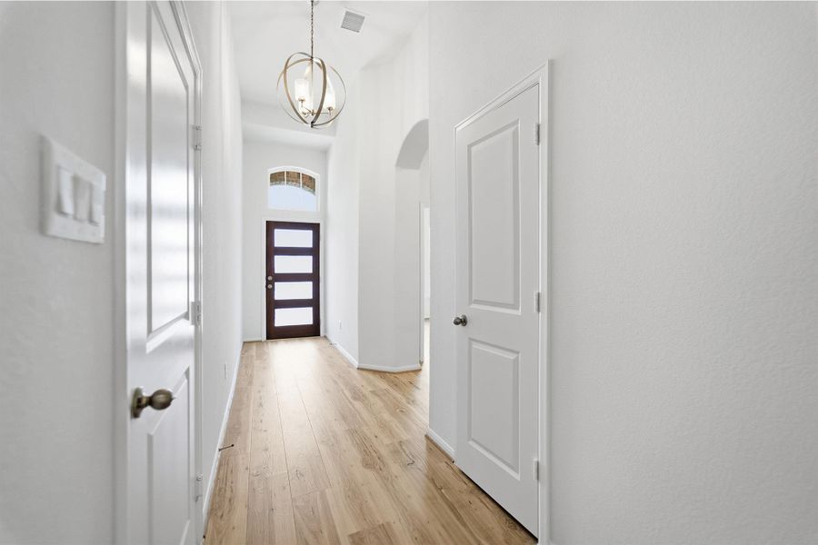 Foyer entrance with light wood-style flooring, a chandelier, and arched walkways