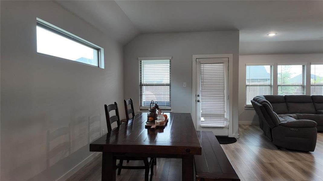 The property features an open layout with light-colored flooring throughout, a door with blinds leading to the outside, and windows with blinds providing natural light