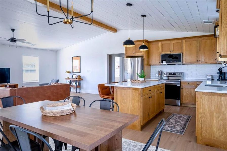 Open-concept living area with a vaulted ceiling and exposed beam