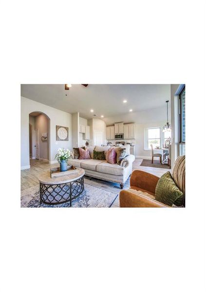 Living room featuring ceiling fan with notable chandelier and light wood-type flooring