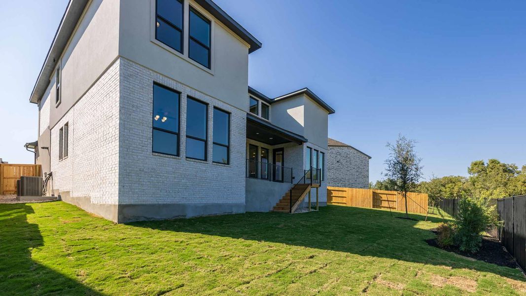 Back of house featuring brick siding, a fenced backyard, stairs, and stucco siding Back of house featuring brick siding, a fenced backyard, stairs, and stucco siding
