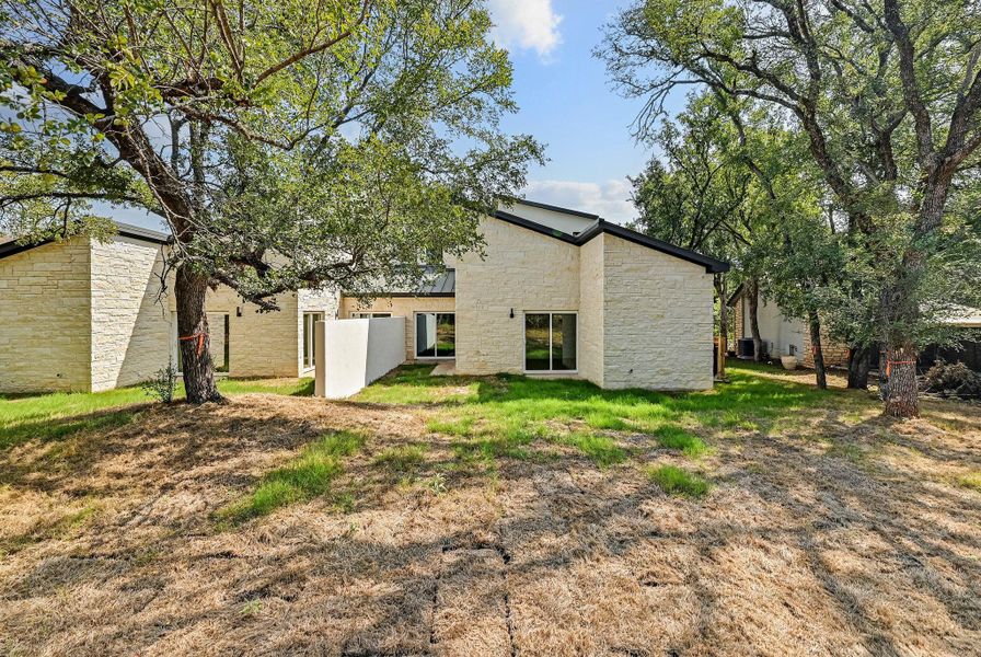 Rear view of house featuring stone siding and a yard