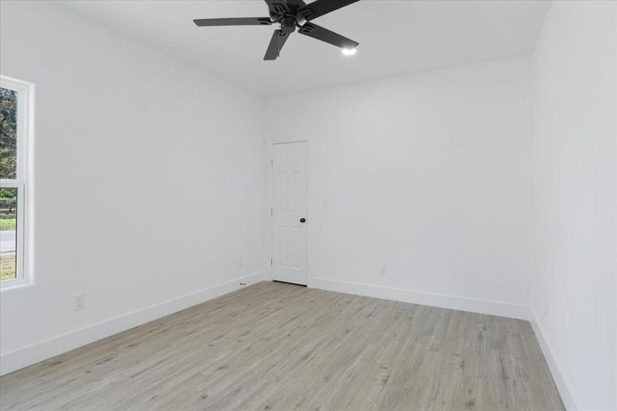 Empty room with light hardwood / wood-style floors and ceiling fan