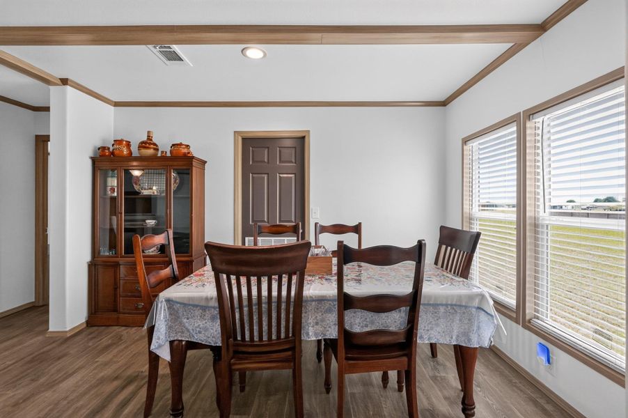 This naturally illuminated dining space features wood-toned flooring and trim, creating a warm, inviting atmosphere for meals.