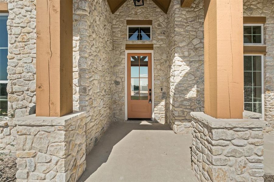 Property entrance featuring stone siding and a porch