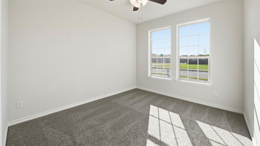 Bright room featuring two large windows with grid patterns, a ceiling fan with integrated lighting, and gray carpet flooring