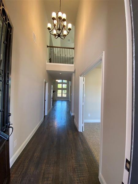 Entrance foyer featuring a high ceiling, a notable chandelier, and dark hardwood  floors