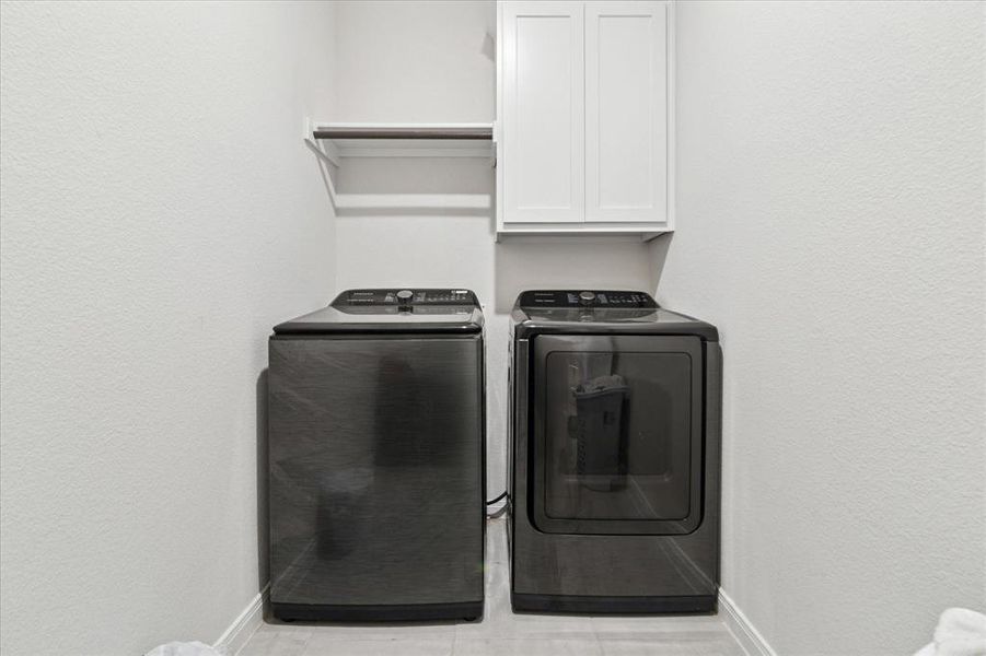 Washroom featuring a textured wall, washing machine and dryer, and cabinet space Washroom featuring a textured wall, washing machine and dryer, and cabinet space