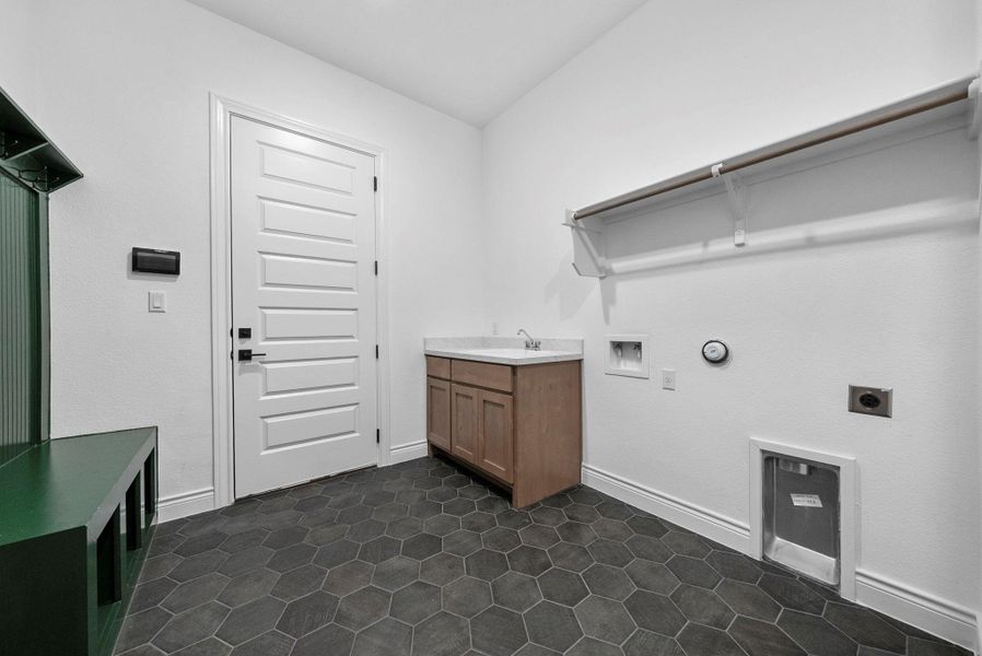 Generous laundry room with built-in cabinetry, utility sink, and space for full-size washer and dryer.