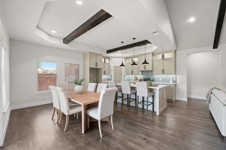 Open-concept living space featuring wood-finish flooring, a tray ceiling with exposed beams, and recessed lighting Open-concept living space featuring wood-finish flooring, a tray ceiling with exposed beams, and recessed lighting