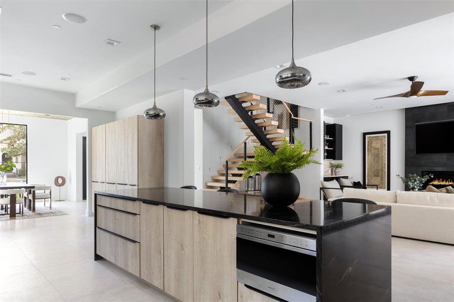 Kitchen featuring light tile patterned flooring, stainless steel oven, ceiling fan, decorative light fixtures, and a large fireplace