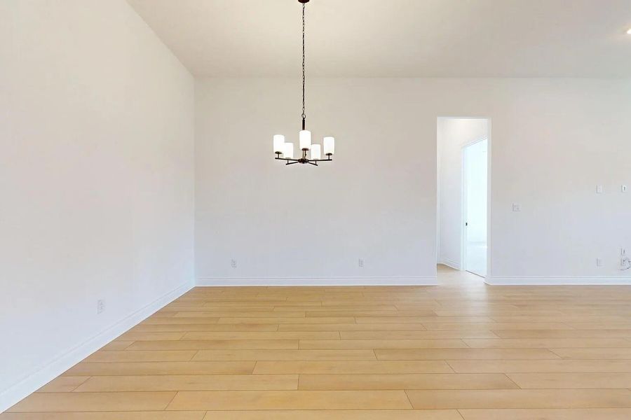 This spacious room features light-colored hardwood floors and white walls, creating a bright and airy atmosphere