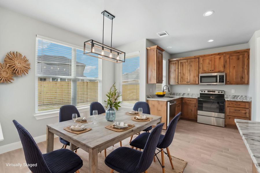 Virtually Staged Kitchen featuring light wood-type flooring, visible vents, appliances with stainless steel finishes, light countertops, and baseboards