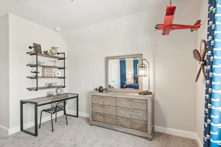 Children's bedroom with aviation theme, wood dresser, desk with wall shelves, and hanging red airplane model Children's bedroom with aviation theme, wood dresser, desk with wall shelves, and hanging red airplane model
