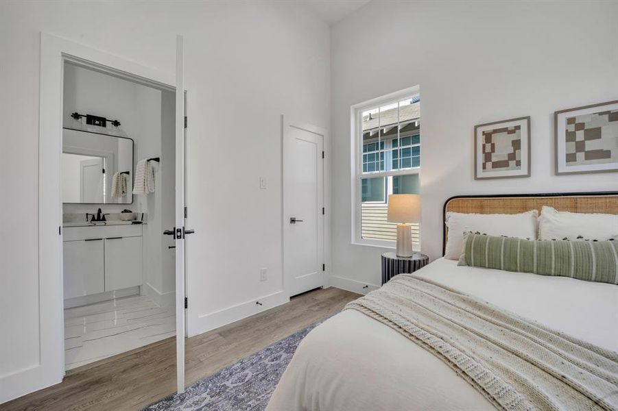 Bedroom with light hardwood / wood-style floors and ensuite bathroom