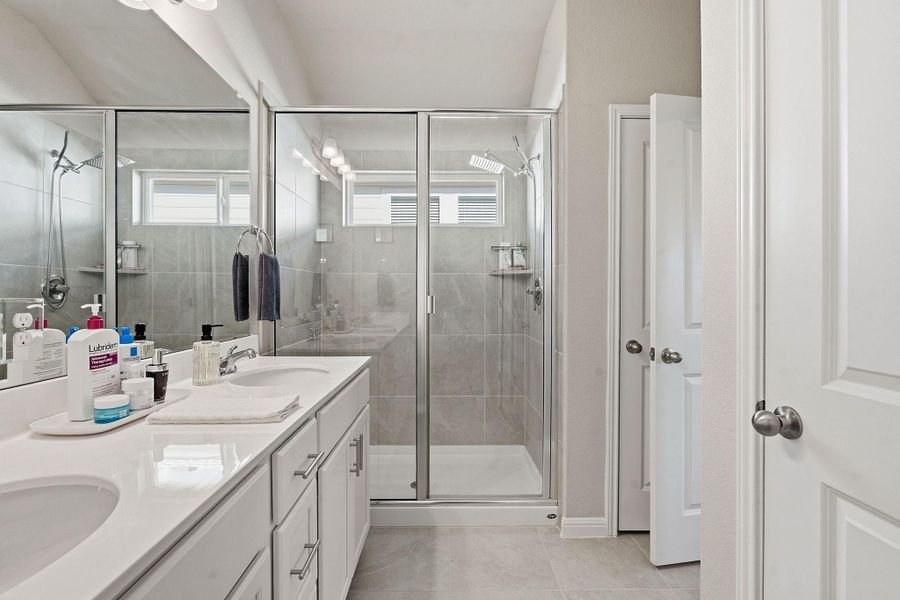 Bathroom with double vanity, a shower stall, and light tile patterned flooring Bathroom with double vanity, a shower stall, and light tile patterned flooring