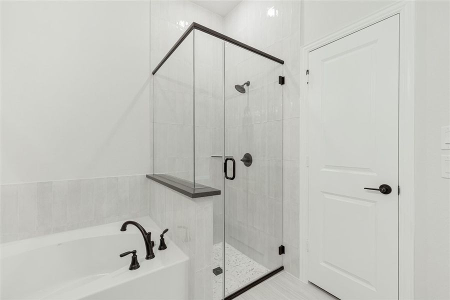 Bathroom with soaking tub and glass-enclosed walk-in shower, white tile walls and black fixtures