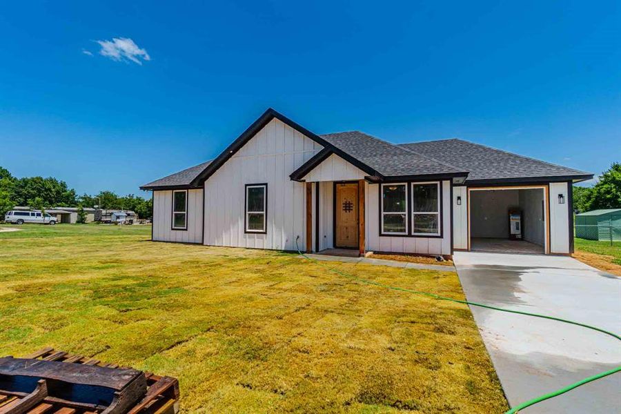 View of front of house with a shingled roof, a front lawn, board and batten siding, concrete driveway, and an attached garage View of front of house with a shingled roof, a front lawn, board and batten siding, concrete driveway, and an attached garage