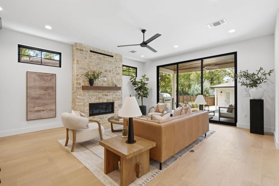 Floor-to-ceiling sliding glass doors frame backyard views alongside a soaring stone fireplace.