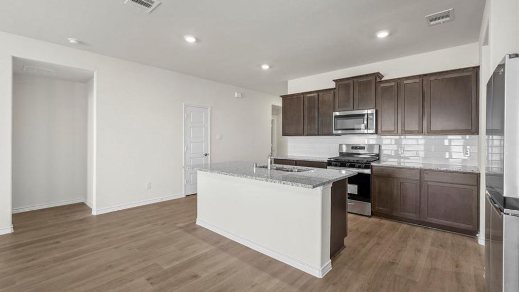 The kitchen features dark wood cabinetry, stainless steel appliances, granite countertops, and a subway tile backsplash