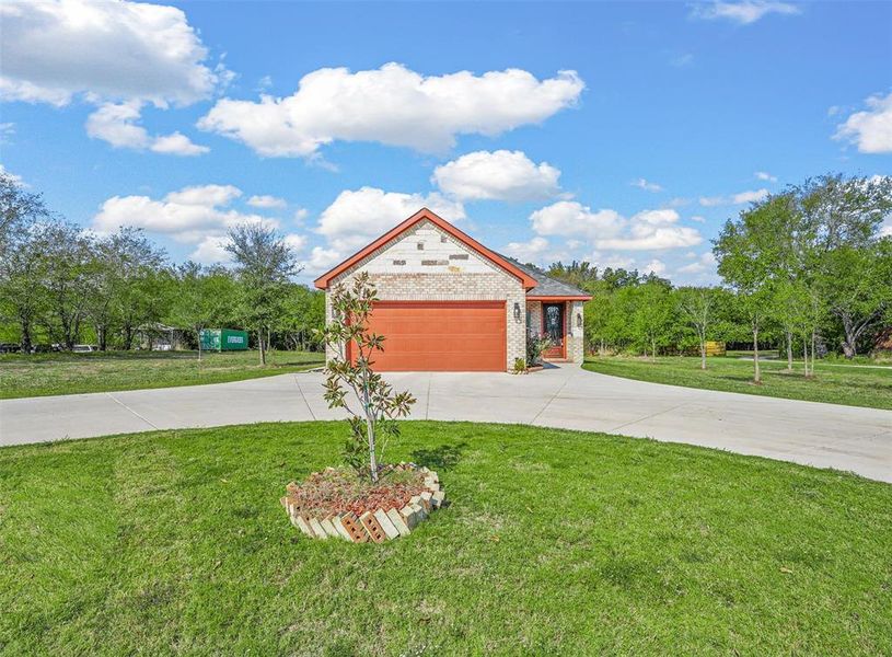 View of front of house featuring a front yard, garage, and circle drive.