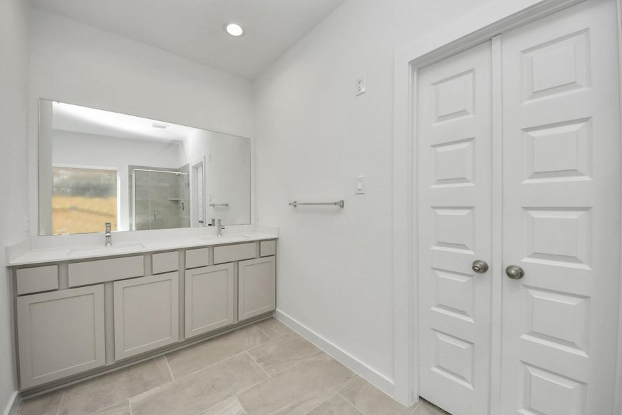 Elevate your daily routine at the elegant vanity, now equipped with double sinks, light countertops, modern hardware, and beautiful recessed lights. Sample photo of completed home with similar floor plan. Actual colors and selections may vary.