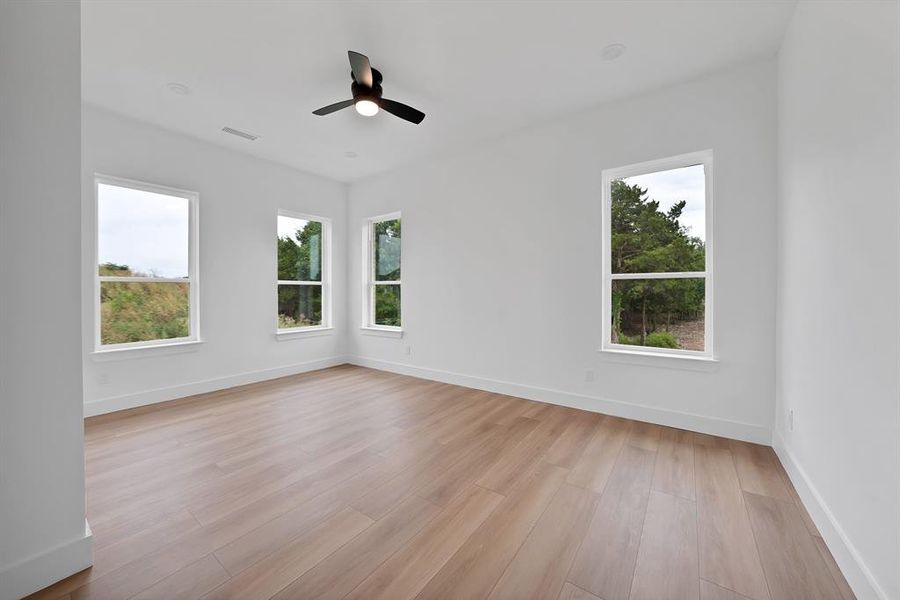 Room featuring wood-finish flooring, white walls, and multiple windows