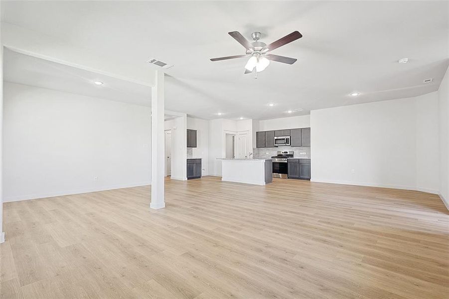 Unfurnished living room with ceiling fan and light wood-type flooring