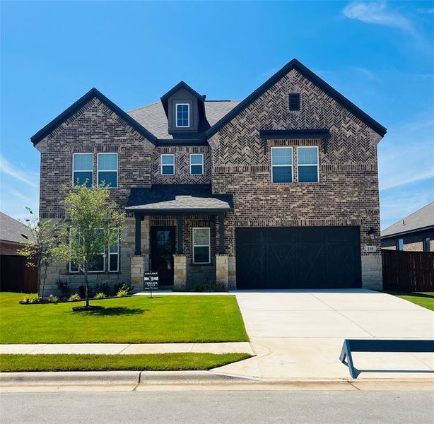 The Yale plan at The Colony is a beautiful two-story home with a long driveway, gorgeous cedar garage door, and lush front yard landscaping.