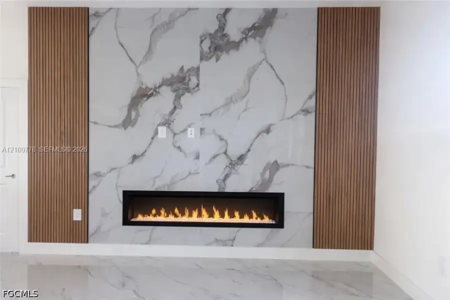 Floor-to-ceiling stone-finish hearth with a linear electric fireplace, flanked by vertical wood-slat accent wall panels Floor-to-ceiling stone-finish hearth with a linear electric fireplace, flanked by vertical wood-slat accent wall panels