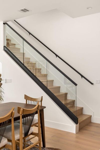 Modern interior staircase features sleek glass railings and natural wood treads.