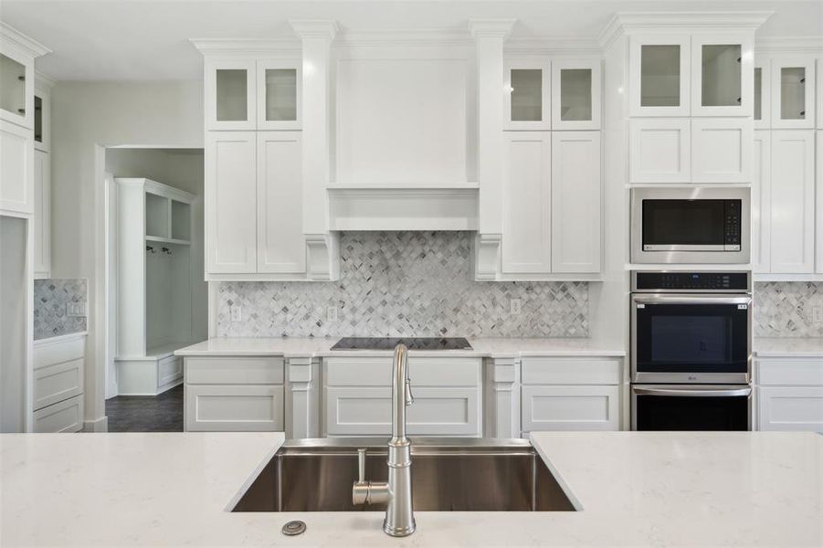 Kitchen featuring decorative backsplash, appliances with stainless steel finishes, light stone counters, sink, and white cabinetry