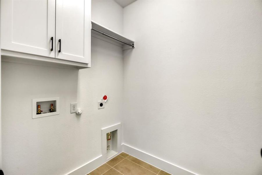 Laundry room featuring hookup for a gas dryer, cabinet space, light tile patterned floors, hookup for a washing machine, and electric dryer hookup