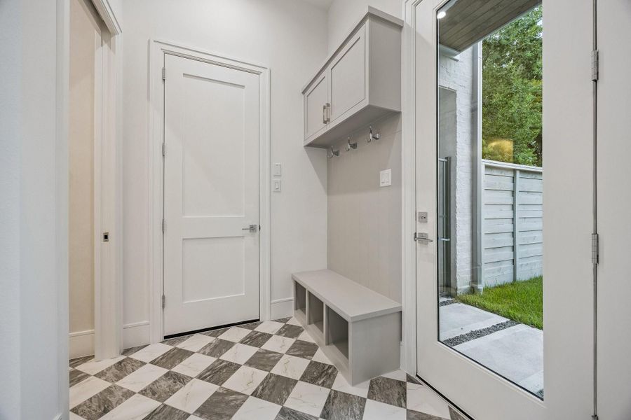 MUD Area off of the garage and the back patio with a 24 x 24 Checkerboard Matte Porcelain Tile in Calcutta and Amani Grey. There is also a built-in bench and hooks.