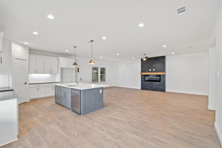 Kitchen with white cabinetry, sink, ceiling fan, light hardwood / wood-style flooring, and an island with sink